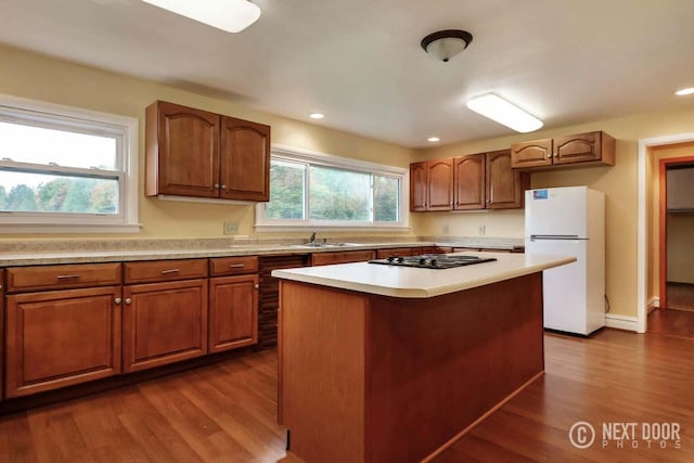 kitchen featuring dark hardwood / wood-style flooring, a center island, a healthy amount of sunlight, and white refrigerator