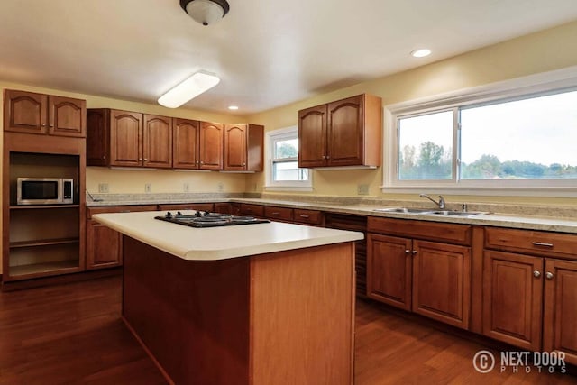 kitchen featuring gas cooktop, dark hardwood / wood-style flooring, a kitchen island, and sink