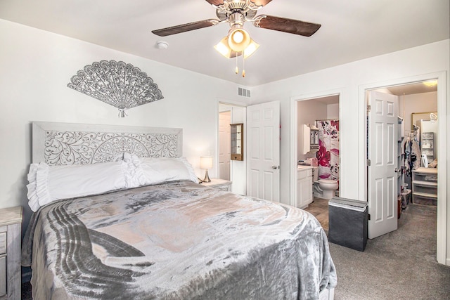 carpeted bedroom with a closet, a walk in closet, ensuite bathroom, and ceiling fan