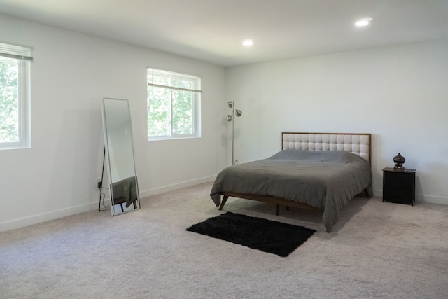 bedroom with light carpet and multiple windows