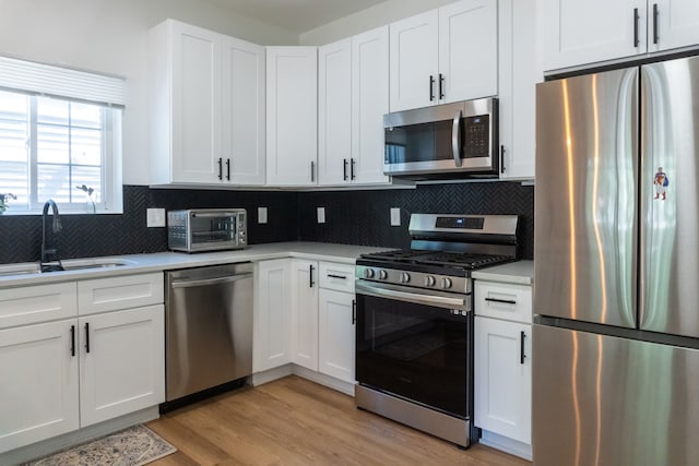 kitchen with white cabinets, light hardwood / wood-style floors, sink, and stainless steel appliances