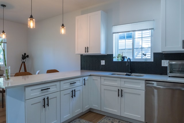 kitchen with kitchen peninsula, sink, hanging light fixtures, stainless steel dishwasher, and white cabinetry