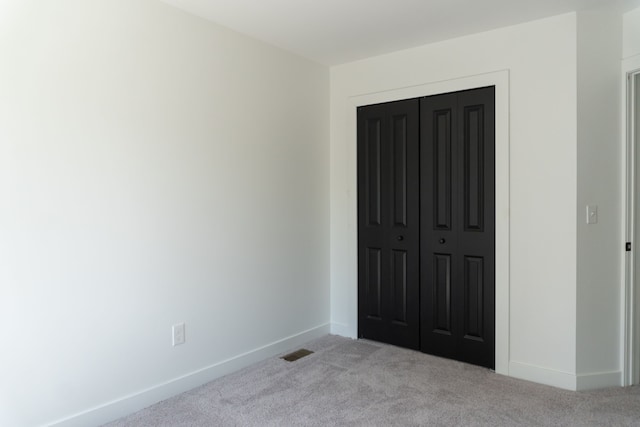 unfurnished bedroom featuring light colored carpet and a closet