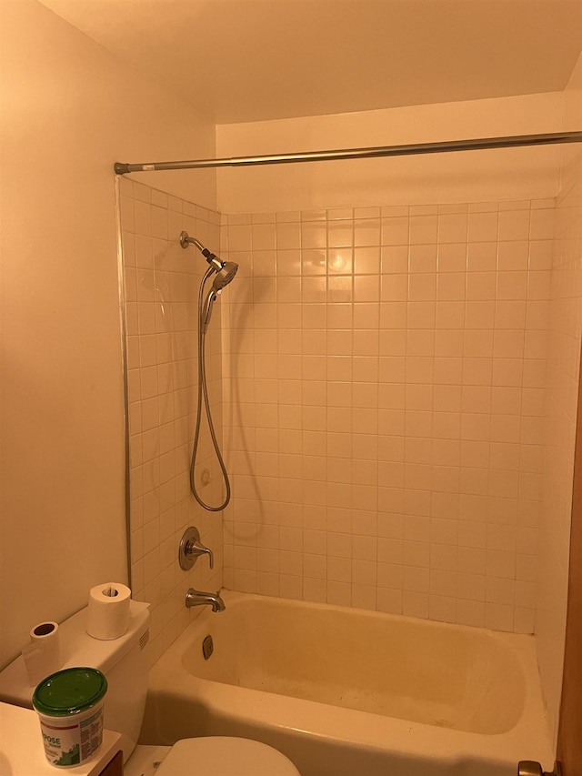 bathroom featuring tiled shower / bath combo and toilet