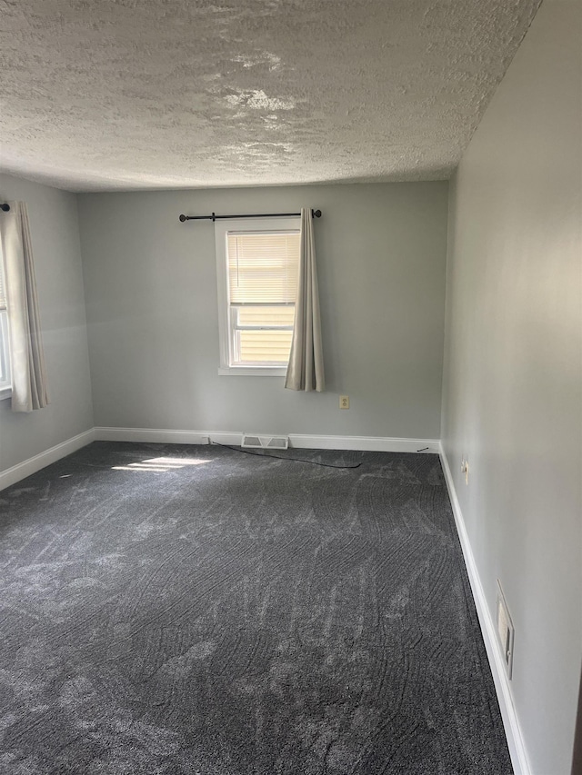 carpeted empty room featuring a textured ceiling