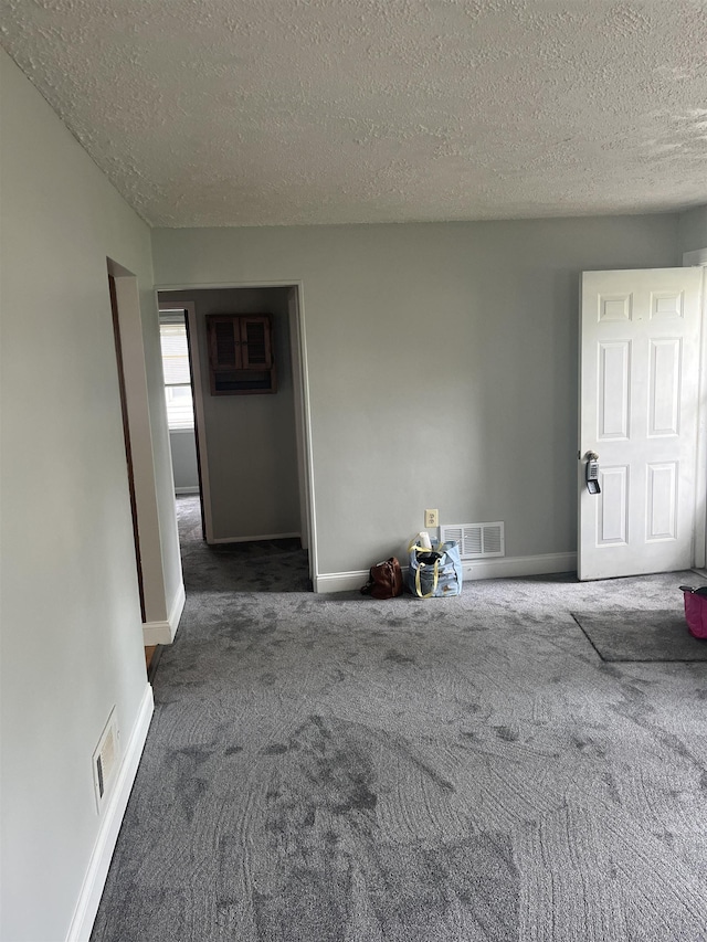 carpeted empty room with a textured ceiling