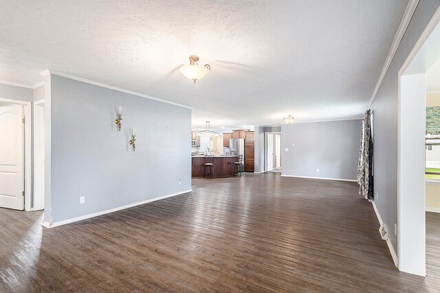 unfurnished living room with dark hardwood / wood-style floors, ornamental molding, and a textured ceiling