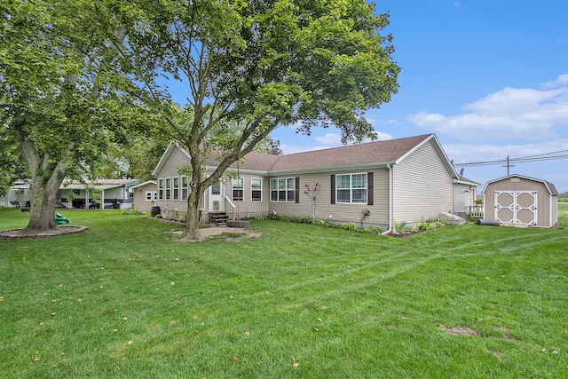 rear view of property featuring a yard and a storage unit