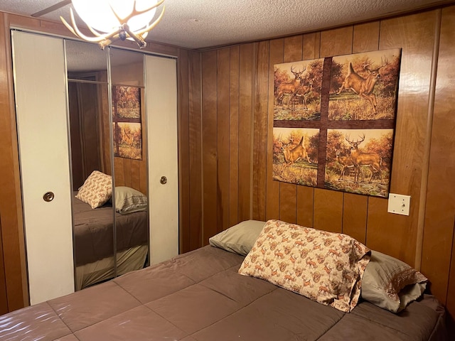 bedroom with wood walls, ceiling fan, and a textured ceiling