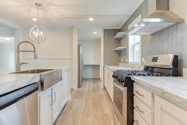 kitchen featuring sink, wall chimney exhaust hood, decorative light fixtures, appliances with stainless steel finishes, and light wood-type flooring