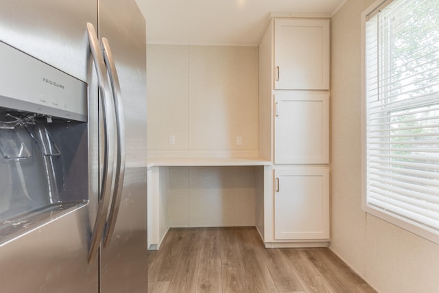 kitchen featuring white cabinets, stainless steel fridge, light hardwood / wood-style floors, and ornamental molding