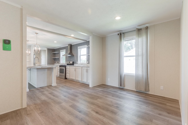 unfurnished living room featuring an inviting chandelier, light hardwood / wood-style flooring, crown molding, and sink