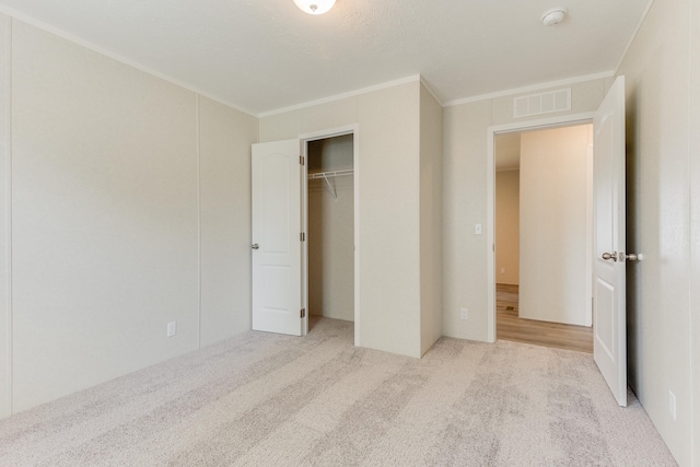 unfurnished bedroom with light colored carpet, crown molding, and a closet