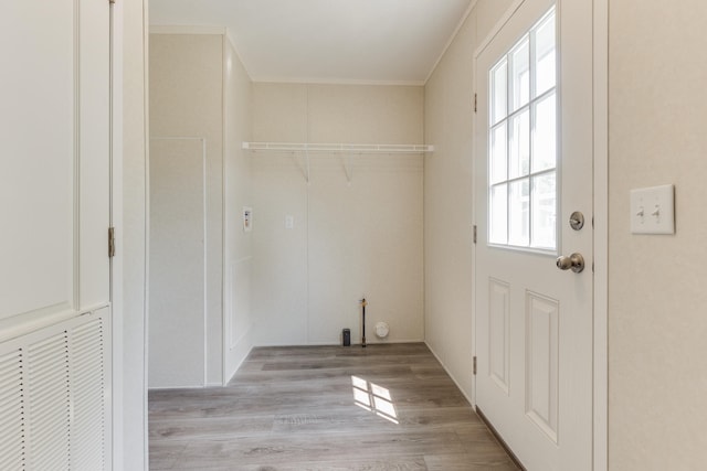 clothes washing area with light hardwood / wood-style floors and ornamental molding