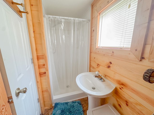 bathroom with wood walls, sink, and a shower with shower curtain