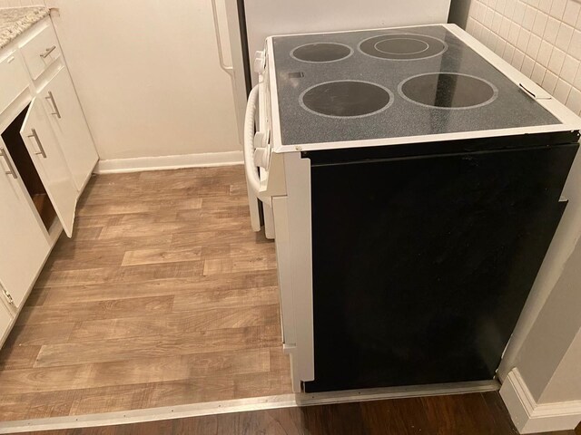 17161 Redford St Unit 203, Detroit, MI 48219 - kitchen view of black / electric stove, light wood finished floors, tasteful backsplash, and white cabinets