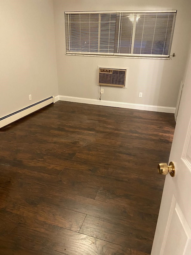 empty room with dark hardwood / wood-style flooring, an AC wall unit, and a baseboard heating unit