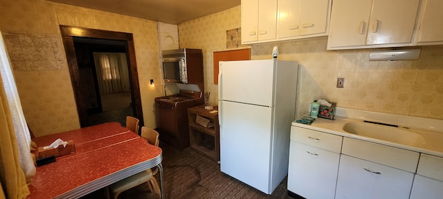 kitchen with white cabinetry, sink, white fridge, and range with gas cooktop