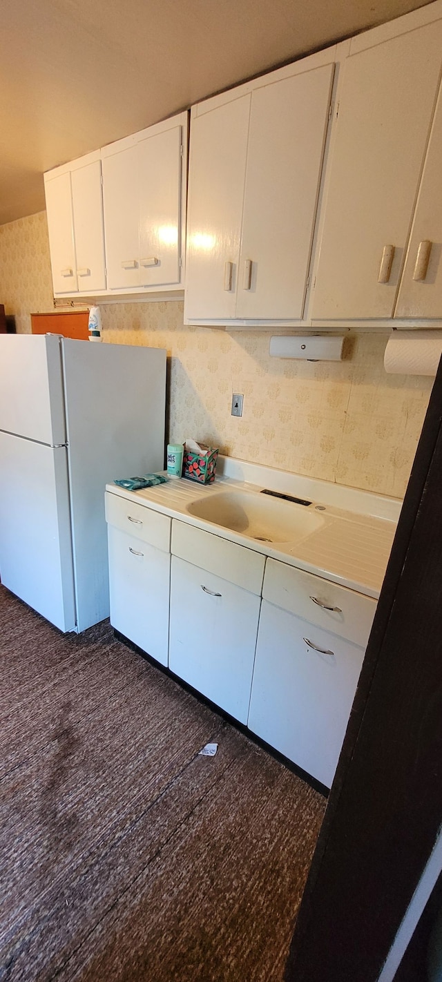 kitchen featuring white fridge, white cabinetry, and sink