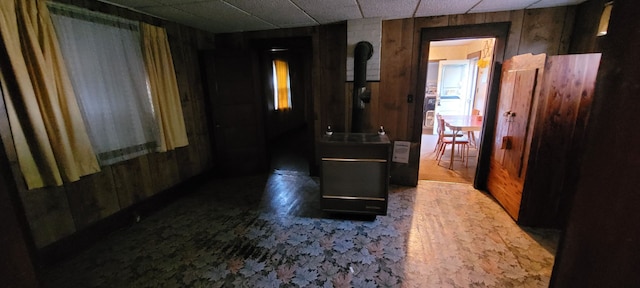 hall featuring a paneled ceiling and wood walls