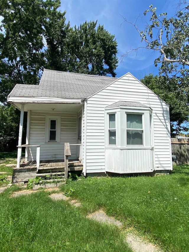 back of property featuring a porch and a yard