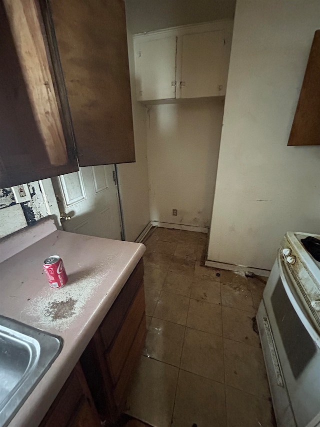 kitchen featuring white cabinets, electric range, and sink