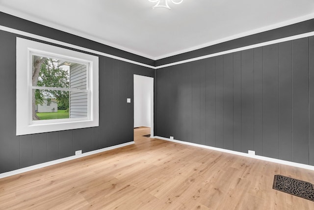 spare room featuring wood walls and light wood-type flooring