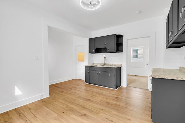 kitchen featuring backsplash, light wood-type flooring, and sink