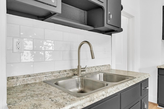 kitchen with decorative backsplash, light wood-type flooring, gray cabinetry, and sink