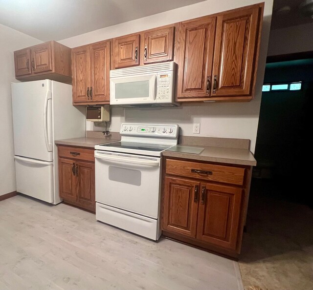 5576 S Whalen Lake Rd, Baldwin, MI 49304 - kitchen with white appliances, brown cabinets, and light wood finished floors