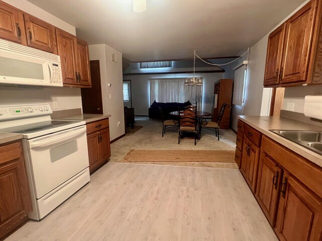 5576 S Whalen Lake Rd, Baldwin, MI 49304 - kitchen with white appliances, brown cabinets, light wood-type flooring, a chandelier, and decorative light fixtures