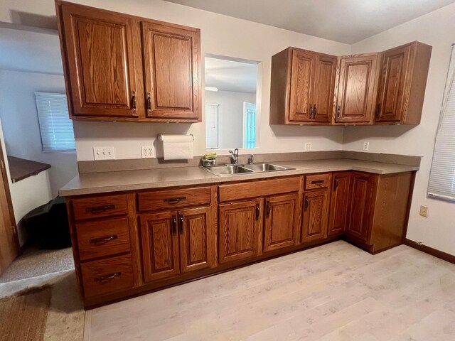 5576 S Whalen Lake Rd, Baldwin, MI 49304 - kitchen featuring a sink, brown cabinetry, light wood finished floors, and baseboards