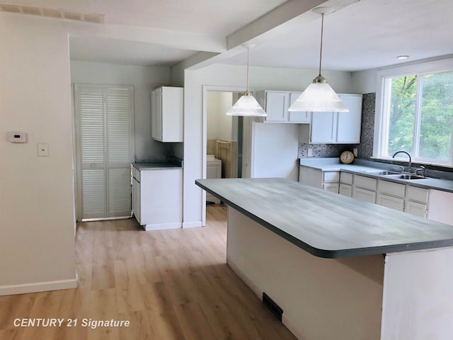 kitchen featuring backsplash, sink, decorative light fixtures, white cabinets, and light hardwood / wood-style floors