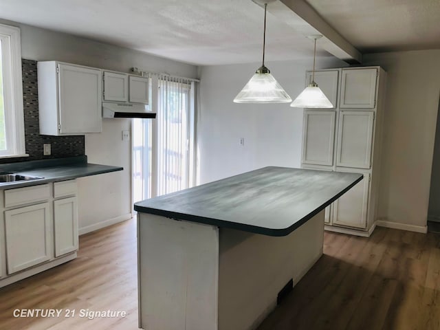 kitchen with backsplash, wood-type flooring, white cabinetry, and hanging light fixtures