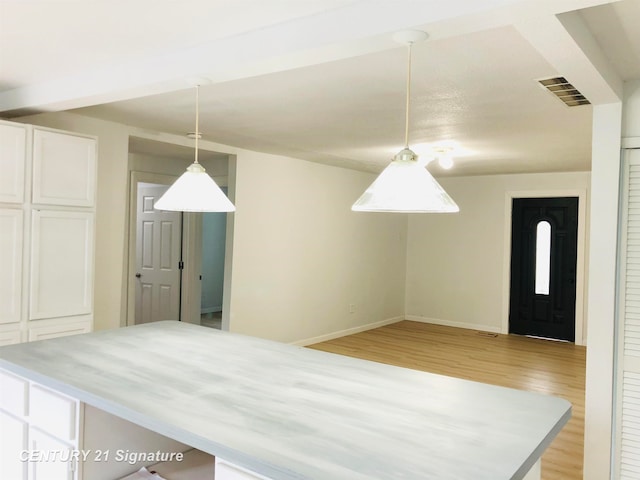 kitchen featuring white cabinetry, light hardwood / wood-style floors, and decorative light fixtures