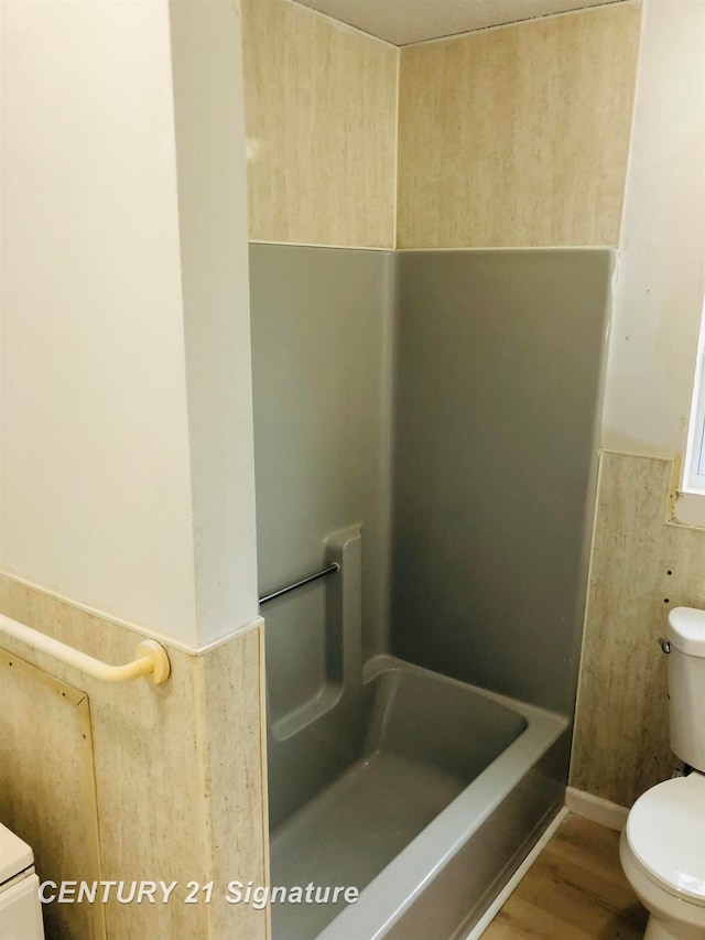 bathroom featuring a bathing tub, toilet, and wood-type flooring