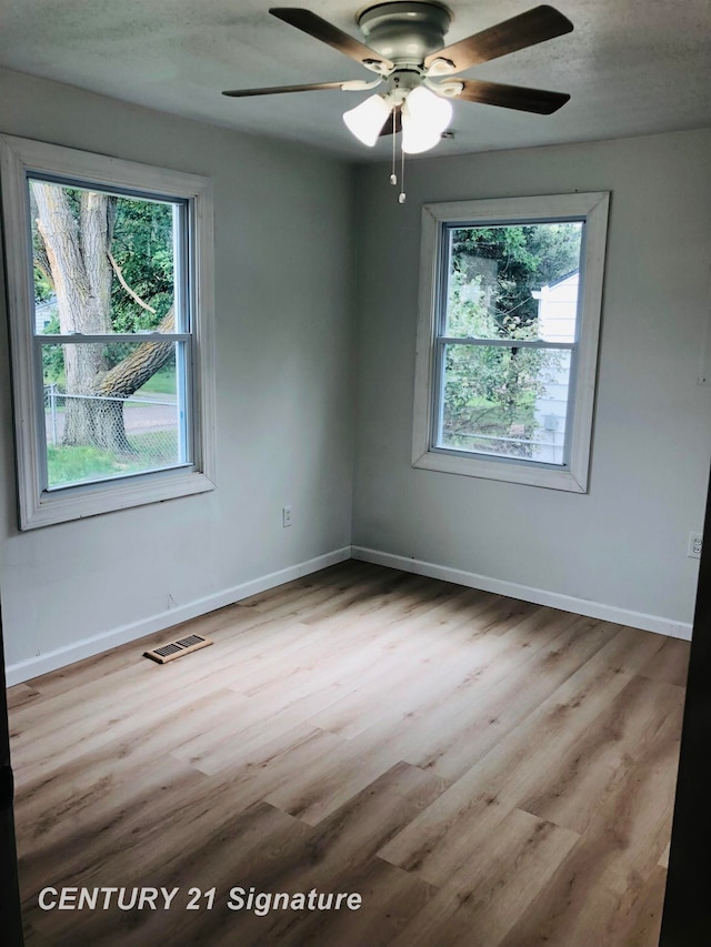 spare room with plenty of natural light, ceiling fan, a textured ceiling, and light hardwood / wood-style flooring