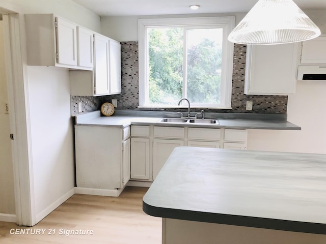 1540 Pound Dr, Flint, MI 48532 - kitchen featuring a sink, backsplash, light wood-style flooring, and white cabinets