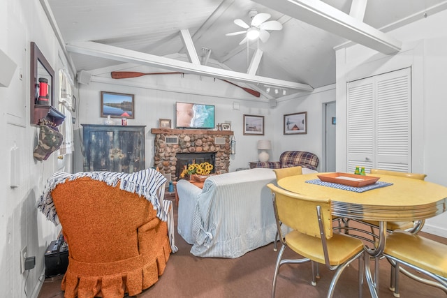 living room with ceiling fan, lofted ceiling with beams, and a stone fireplace