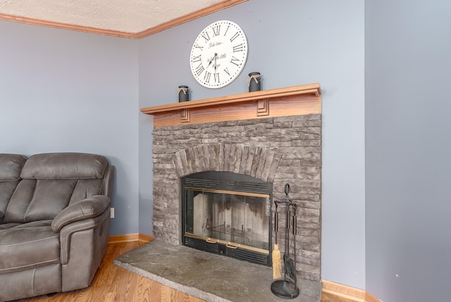 room details with a stone fireplace, wood-type flooring, a textured ceiling, and ornamental molding