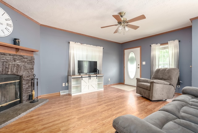 living room with ceiling fan, light hardwood / wood-style floors, a stone fireplace, and a textured ceiling