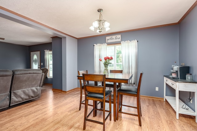 dining room featuring ornamental molding, light hardwood / wood-style floors, a textured ceiling, and a notable chandelier