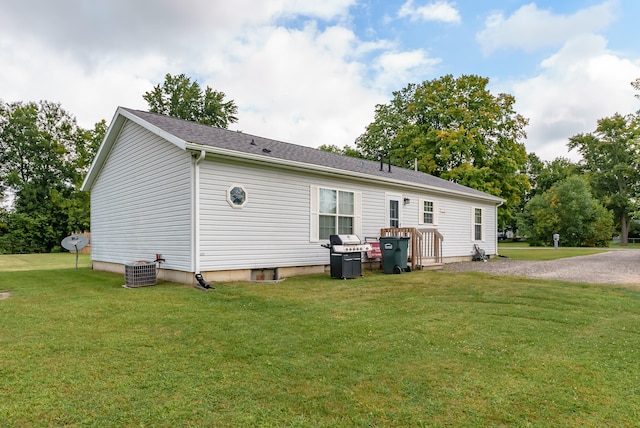 rear view of property featuring a yard and central AC unit