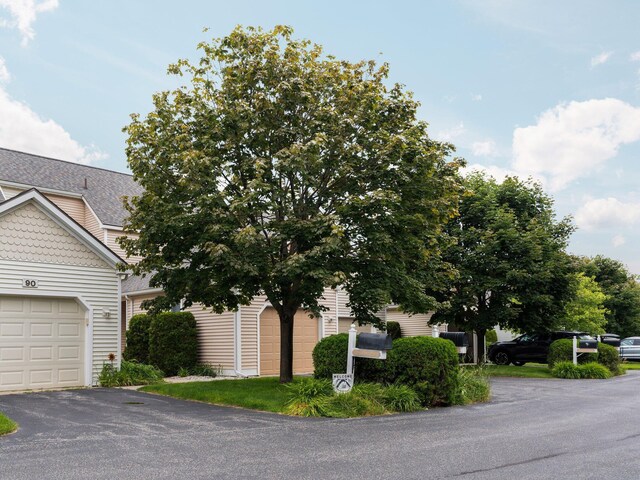 94 Charter Ct, Manistee, MI 49660 - obstructed view of property with a garage, a shingled roof, and asphalt driveway