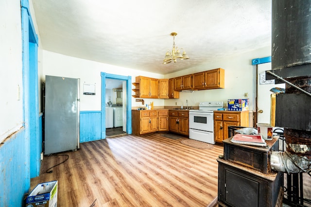 kitchen featuring refrigerator, white range with electric stovetop, an inviting chandelier, washing machine and dryer, and hanging light fixtures