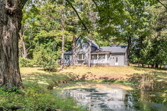 rear view of house with a yard and a water view