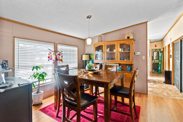 dining space featuring light hardwood / wood-style floors, crown molding, and a textured ceiling