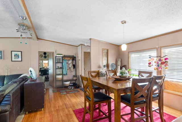 dining area featuring light wood-type flooring, a textured ceiling, vaulted ceiling with beams, and ornamental molding