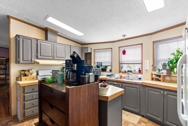 kitchen featuring a textured ceiling, gray cabinets, sink, and hanging light fixtures