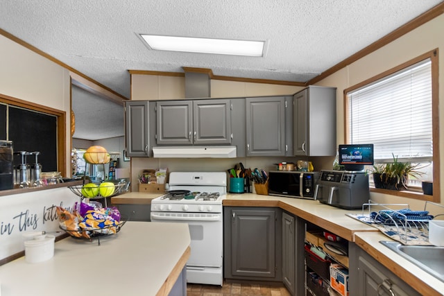 kitchen with a textured ceiling, vaulted ceiling, gas range gas stove, and gray cabinetry